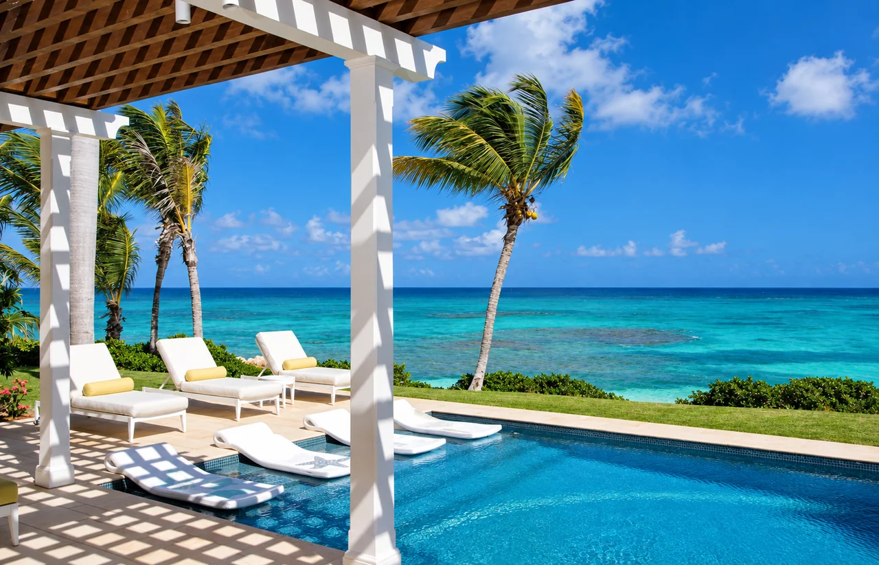 A shaded villa terrace with white loungers and a pool overlooking the sea in Antigua