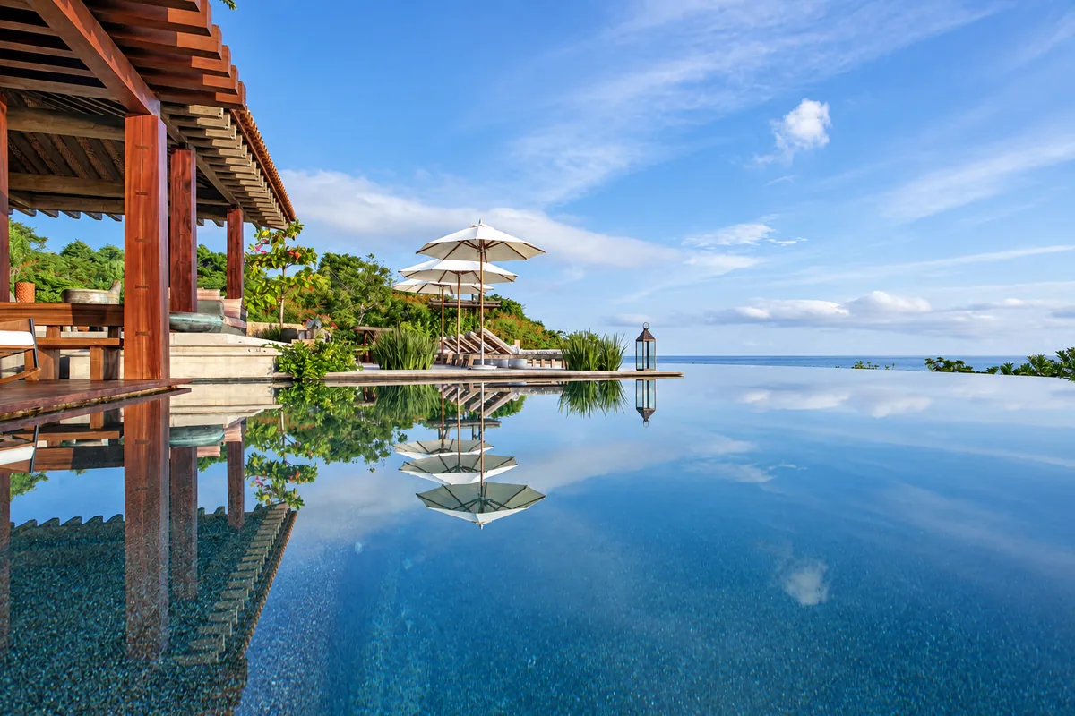 A reflecting infinity pool beside a wooden pavilion overlooking the sea