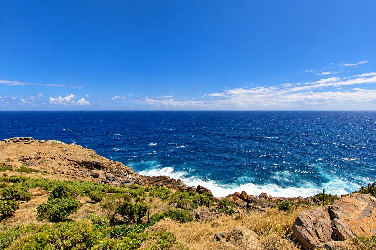 A rocky coastal headland above deep blue water and breaking waves in St. Barts