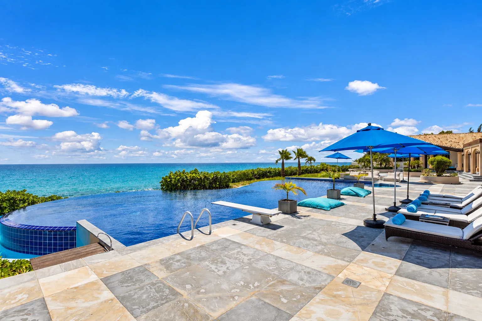 An oceanfront infinity pool and villa terrace with blue parasols in St. Martin